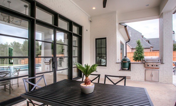 Patio with large iron doors and windows looking into homee