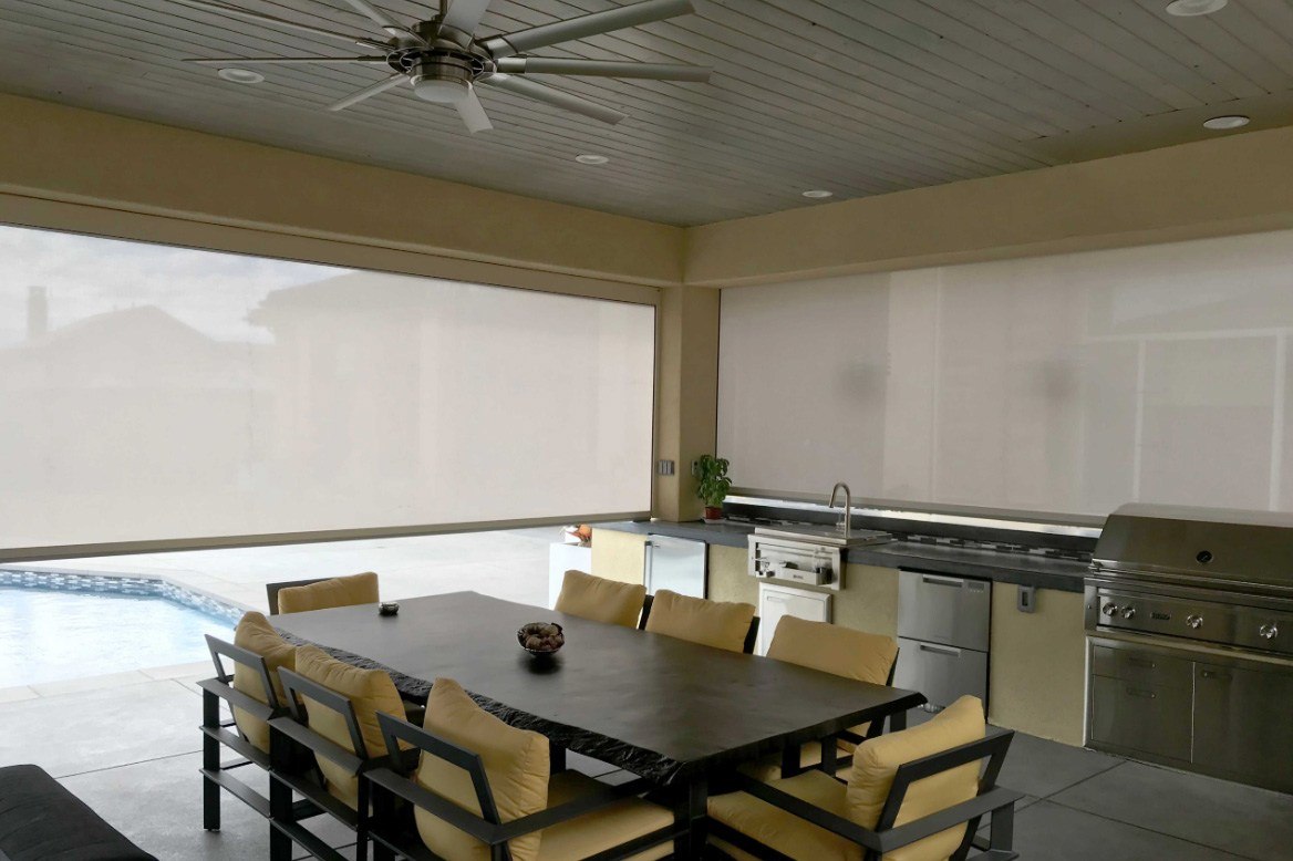 Outdoor kitchen and dining area enclosed with patio shade