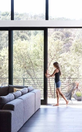 Woman opening the sliding glass wall in her home