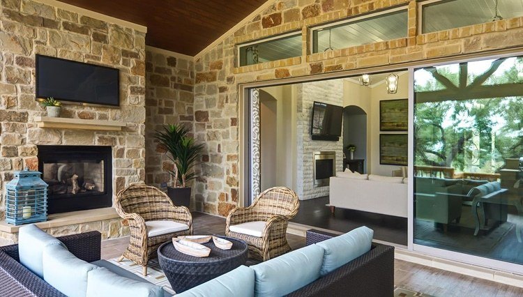 Sliding glass wall separating outdoor living space with fireplace opening on to living