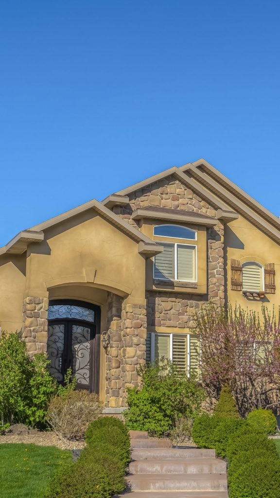 a view of a home with a landscaped yard and iron door