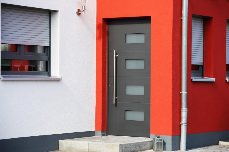 The outside of a red building with a modern iron door 
